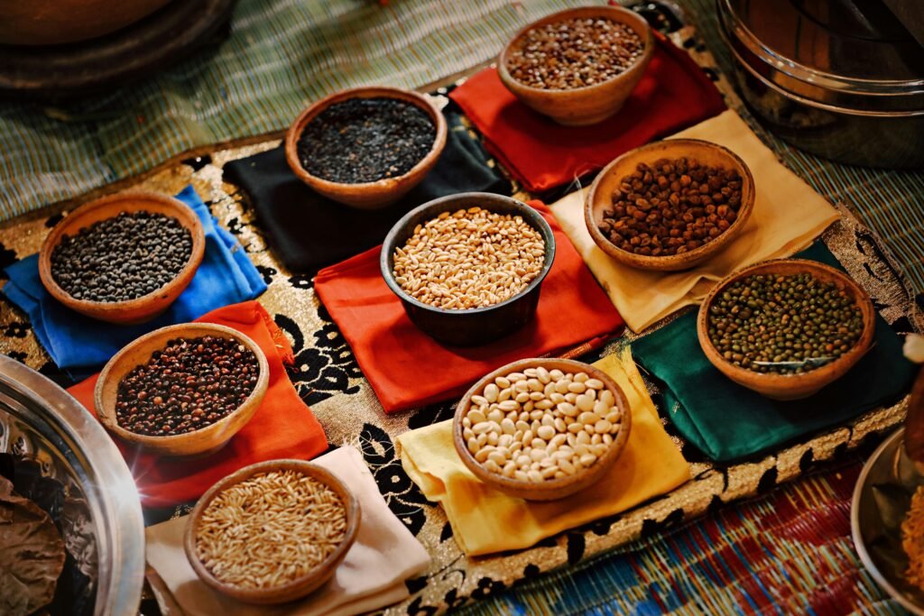 A vibrant assortment of grains and beans in ceramic bowls arranged on colorful textiles, showcasing diverse ingredients.